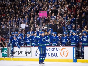 Vancouver Canucks' Henrik Sedin, front, of Sweden, waves as he receives a standing ovation from his teammates on the bench and the crowd after scoring a goal against the Florida Panthers to record his 1,000th career point, during the second period of an NHL hockey game in Vancouver, B.C., on Friday January 20, 2017.