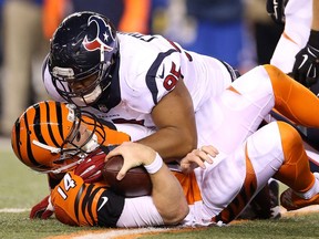 Houston Texans defensive lineman Christian Covington (on top) gets familiar with Cincinnati Bengals quarterback Andy Dalton after sacking the pivot during a November 2015 NFL game in Cincinnati.