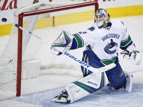 Vancouver Canucks goalie Jacob Markstrom, of Sweden, knocks the puck away during third period NHL hockey action against the Calgary Flames in Calgary, Saturday, Jan. 7, 2017.