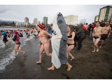 A man dressed in a shark costume and other participants run into the waters of English Bay during the Polar Bear Swim, in Vancouver, B.C., on Sunday, January 1, 2017. The event, hosted by the Vancouver Polar Bear Swim Club, was first held on new year's day in 1920.