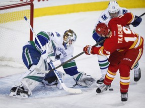 Vancouver Canucks goalie Jacob Markstrom, left, of Sweden, grabs for the puck as Calgary Flames' Matthew Tkachuk looks on during third period NHL hockey action in Calgary, Saturday, Jan. 7, 2017.