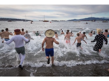 Participants run into the frigid waters of English Bay during the Polar Bear Swim in Vancouver, B.C., on Sunday, January 1, 2017. The event, hosted by the Vancouver Polar Bear Swim Club, was first held on new year's day in 1920.