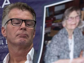 Price Carter, left, son of Kay Carter, in photo in foreground, pauses for a moment during a B.C. Civil Liberties news conference in Vancouver on June 6, 2016. Price and his sister, Lee Carter, were speaking on the Supreme Court of Canada's death-with-dignity ruling.