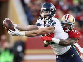 Tanner McEvoy of the Seattle Seahawks catches the ball while covered by Dontae Johnson of the San Francisco 49ers on Sunday in Santa Clara, Calif. The Seahawks fell behind 14-3 but won 25-23. They face the Detroit Lions in the playoffs Saturday.