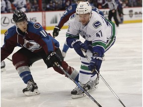 Sven Baertschi fights for control of the puck with Avalanche defenseman Cody Goloubef.