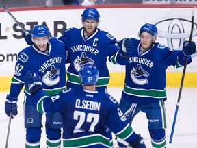 Vancouver Canucks' Sven Baertschi, top left to right, Henrik Sedin, of Sweden, Troy Stecher and Daniel Sedin, bottom, of Sweden, celebrate Baertschi's second goal against the Colorado Avalanche during the third period of an NHL hockey game in Vancouver, B.C., on Monday January 2, 2017.