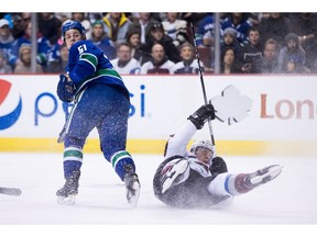 Colorado Avalanche's Nathan MacKinnon, right, falls to the ice after colliding with Vancouver Canucks' Troy Stecher during the first period of an NHL hockey game in Vancouver, B.C., on Monday January 2, 2017.