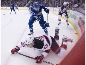 Vancouver Canucks centre Brandon Sutter (20) fights for control of the puck with New Jersey Devils left wing Michael Cammalleri (13) and centre Travis Zajac (19) during first period NHL action in Vancouver, B.C. Sunday, Jan. 15, 2017.