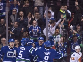 Vancouver Canucks centre Michael Chaput (45) celebrates his goal with his teammates as Calgary Flames left wing Johnny Gaudreau (13) looks on during first period NHL action in Vancouver, B.C. Friday, Jan. 6, 2017.