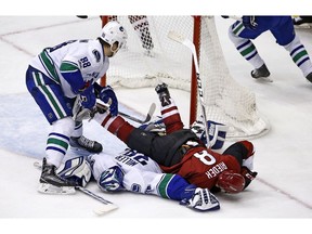 Vancouver Canucks defenseman Nikita Tryamkin (88) slams Arizona Coyotes right wing Tobias Rieder (8) onto Canucks goalie Ryan Miller during the third period of an NHL hockey game Thursday, Jan. 26, 2017, in Glendale, Ariz. The Coyotes defeated the Canucks 3-0.