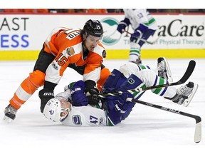 Michael Del Zotto of the Philadelphia Flyers flattens Sven Baertschi of the Vancouver Canucks during NHL action on Thursday, Jan. 12, at Wells Fargo Center in Philadelphia. The Flyers won 5-4 in a shootout.