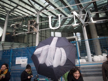 A woman holds an umbrella with an image of a middle finger displayed, outside the still under construction Trump International Hotel and Tower during a women's march and protest against U.S. President Donald Trump, in Vancouver, B.C., on Saturday January 21, 2017. Protests are being held across Canada today in support of the Women's March on Washington. Organizers say 30 events in all have been organized across Canada, including Ottawa, Toronto, Montreal and Vancouver.