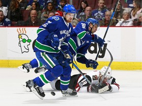 Daniel Sedin and Brandon Sutter check Jamie McGinn.