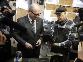 Finance Minister Mike de Jong picks up his newly soled shoes from Mike Waterman at Olde Towne Shoe Repair in Victoria on Monday. De Jong is promising to share the benefits of B.C.'s economic prosperity with taxpayers in Tuesday's provincial budget.