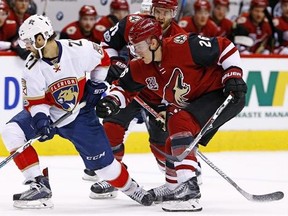 Florida Panthers center Vincent Trocheck (21) battles with Arizona Coyotes defenseman Michael Stone (26) and defenseman Alex Goligoski (33) for the puck during the first period of an NHL hockey game, Monday, Jan. 23, 2017, in Glendale, Ariz. The Calgary Flames have acquired defenceman Michael Stone from the Arizona Coyotes for two draft picks. THE CANADIAN PRESS/AP, Ross D. Franklin