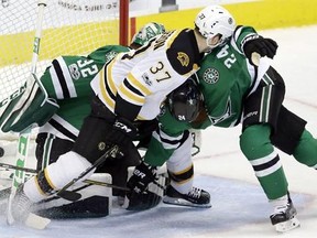 Boston Bruins center Patrice Bergeron (37) gets the puck into the net to score a goal against Dallas Stars defenseman Jordie Benn (24) and goalie Kari Lehtonen (32) during the second period of an NHL hockey game in Dallas, Sunday, Feb. 26, 2017. (AP Photo/LM Otero)