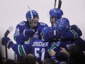 Vancouver Canucks right wing Alexandre Burrows (14) celebrates teammate defencman Christopher Tanev's (8) game-winning goal against the Calgary Flames with teammates during overtime NHL hockey action in Vancouver on Saturday, February 18, 2017.