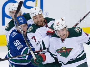 Vancouver Canucks forward Brendan Gaunce gets tangled up with Minnesota Wild's Chris Stewart, centre, Tyler Graovac and Charlie Coyle, back left, during the third period of Saturday's game at Rogers Arena.