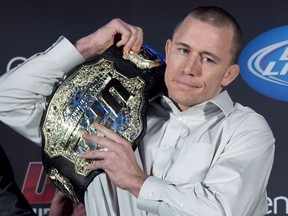 Welterweight UFC champion Georges St-Pierre puts his belt on his shoulder during a news conference in Montreal on Jan. 23, 2013.