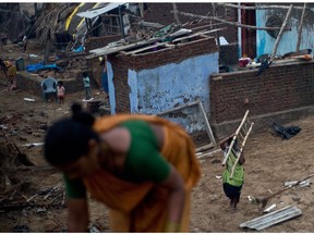 An Indian woman carries a wooden ladder to fix her house damaged during Cyclone Phailin at Nalianuagaon in the Ganjam district of Odisha on Oct. 15, 2013.
