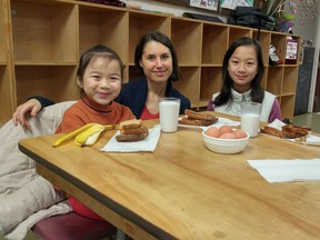Lauren Brown, food security co-ordinator of the Strathcona Community Centre, visits with with sisters Lisa, 7 and Leena, 12, as they eat. The Strathcona Community Centre Association is asking the Vancouver Park Board to provide $200,000 a year in funding for the meals program and other services. (PNG FILES)
