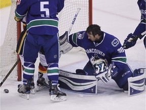 Ryan Miller  catches his mask in his glove after falling off after a shot from the Flames during the second period.