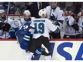 Joe Thornton hits Alex Edler into the Sharks' bench.