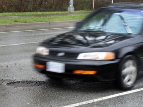 A car attempts to drive around a pothole on King George Boulevard in Surrey.
