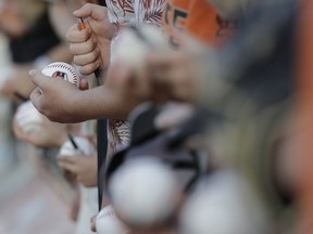 A fan holds a baseball before a spring training baseball game between the San Francisco Giants and the Colorado Rockies, Friday, March 17, 2017, in Scottsdale, Ariz.