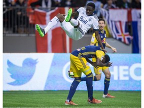 Vancouver Whitecaps' Alphonso Davies, top, falls to the ground after attempting to get his head on the ball against New York Red Bulls' Derrick Etienne during second half CONCACAF Champions League quarter-final soccer action in Vancouver, B.C., on Thursday, March 2, 2017.