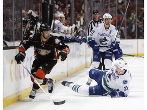 Andrew Cogliano, left, skates past Henrik Sedin.