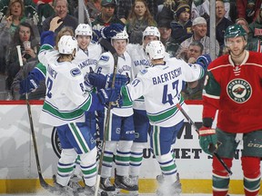 Vancouver Canucks Brock Boeser, back, who was signed the day before, is congratulated by Ben Hutton after Boeser scored against Wild goalie Darcy Kuemper, as Boeser made his NHL debut during a game Saturday in St. Paul, Minn.