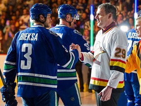 Canucks tough guys Kevin Bieksa (left) and Gino Odjick exchange greetings before a game against the Edmonton Oilers on April, 11, 2015 at Rogers Arena.
