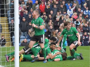 Lincoln City's English defender Sean Raggett, centre, celebrates with teammates after scoring  during the English FA Cup fifth round football match between Lincoln City and Burnley at the Sincil Bank stadium in Lincoln, eastern England, in February.