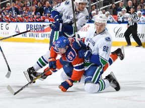 Connor McDavid gets tangled up with Nikita Tryamkin of the Canucks.