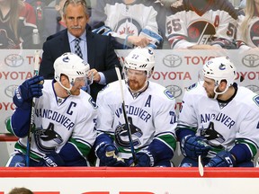 Henrik Sedin, Daniel Sedin and Michael Chaput discuss strategy on the bench.