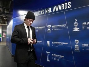 Brock Boeser checks his phone as he walks to the team dressing room before their NHL game against the Ducks.