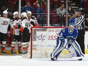 Ryan Miller looks on as Patrick Eaves of the Ducks is congratulated by teammates after scoring.