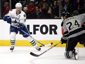 Henrik Sedin passes the puck past Derek Forbort during the first period of an NHL hockey game in Los Angeles, Saturday, March 4, 2017.