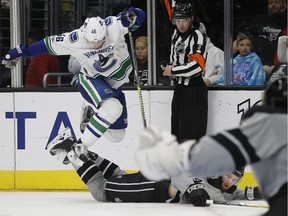 Vancouver Canucks center Jayson Megna, left, leaps over Los Angeles Kings defenseman Derek Forbort, below right, but is called for a tripping penalty by referee Jon McIsaac, center, during the third period of an NHL hockey game in Los Angeles, Saturday, March 4, 2017. The Canucks won 4-3.