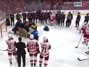 Red Wing and Hurricane players surround Eddie Lack as he's stretchered off the ice.