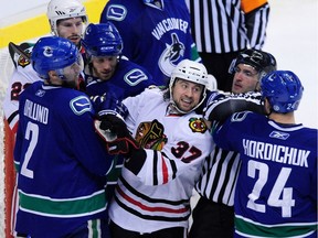 Canucks including Darcy Hordichuk (24) and Mattias Ohlund (2) surround Chicago Blackhawks right winger Adam Burish (37) during a second-round game in the Stanley Cup playoffs at GM Place Stadium in Vancouver on April 30, 2009.