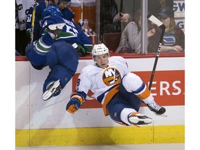 Alex Biega crashes into the boards with Ryan Strome.