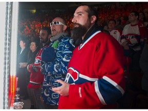 A Canucks fan is sandwiched between Montreal Canadiens fans at a regular season NHL hockey game at Rogers arena on March 07 2017.