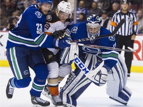 Anaheim Ducks Jakob Silfverberg is sandwiched between the Canucks' Alex Edler and goalie Ryan Miller during the second period of a regular-season NHL game at Rogers Arena in Vancouver on March 28. PUBLISHED TO SUN & PROV