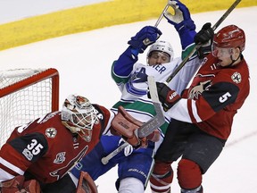 Arizona Coyotes' Connor Murphy (5) tangles with Vancouver Canucks' Bo Horvat, middle, as Coyotes goalie Louis Domingue (35) looks for the puck during the third period of an NHL hockey game Thursday, April 6, 2017, in Glendale, Ariz.  The Coyotes defeated the Canucks 4-3.