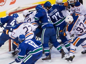 Vancouver Canucks' Drew Shore (42), Alex Biega (55), and Ben Hutton (27) dig for the puck under Edmonton Oilers goalie Cam Talbot as Milan Lucic (27), Oscar Klefbom (77), of Sweden, Ryan Nugent-Hopkins (93), Adam Larsson (6), of Sweden, and Jordan Eberle (14) defend during third period NHL hockey action in Vancouver, B.C., on Saturday, April 8, 2017.