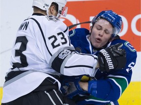 Los Angeles Kings' Dustin Brown, left, checks Vancouver Canucks' Troy Stecher during the third period of Friday's game at Rogers Arena. Stecher got pranked by a fake starting lineup that listed him lining up with the Sedins, but that actually couldn't be any worse that the current winger.