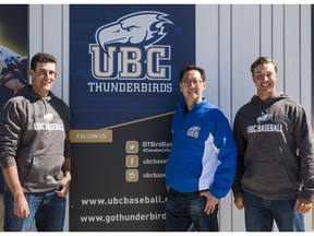 Former UBC baseball players Alex Webb, left, and Bruce Yari, right, huddle with UBC president Santa Ono by their team's emblem.