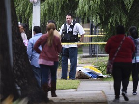 A Fresno police detective stands over the body of one of the three shooting victims Tuesday, April 18, 2017 in Fresno, Calif.